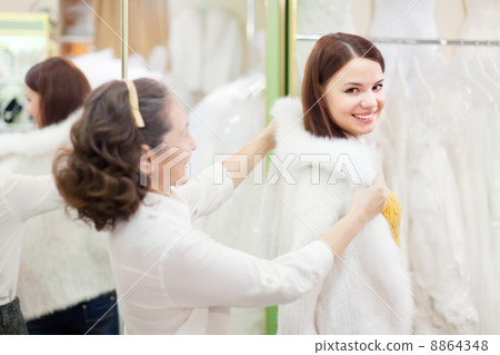 woman with girl chooses white fur cape at shop woman with girl chooses white fur cape at shop 8864348