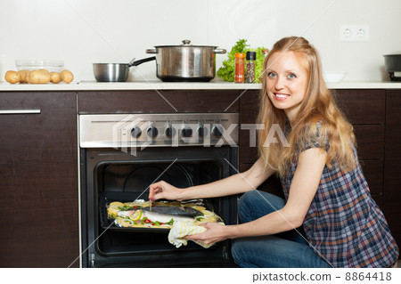 woman cooking saltwater fish in oven at kitchen woman cooking saltwater fish in oven at kitchen 8864418