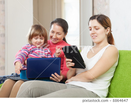 Two women and child looks devices 8864647