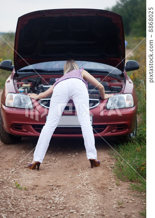 Sexy girl looking under car hood Sexy girl looking under car hood 8868025