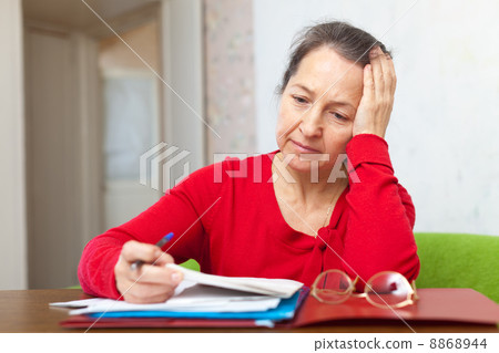 Sad mature woman reads documents Sad mature woman reads documents 8868944
