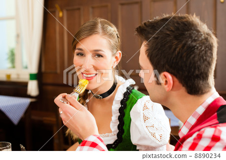 Young couple in traditional Bavarian Tracht eating in restaurant or pub Young couple in traditional Bavarian Tracht eating in restaurant or pub 8890234