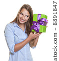 Laughing woman listens on a christmas gift 8891847