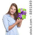 Attractive woman has a gift with ribbon in her hand 8891849