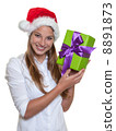 Beautiful woman with christmas hat has a gift in her hands 8891873