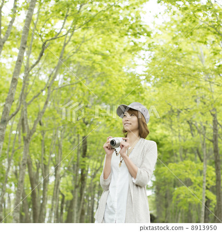 A woman holding a mirrorless single-lens camera and smiling A woman holding a mirrorless single-lens camera and smiling 8913950