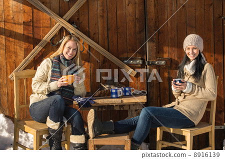 Two young women enjoy tea winter cottage Two young women enjoy tea winter cottage 8916139