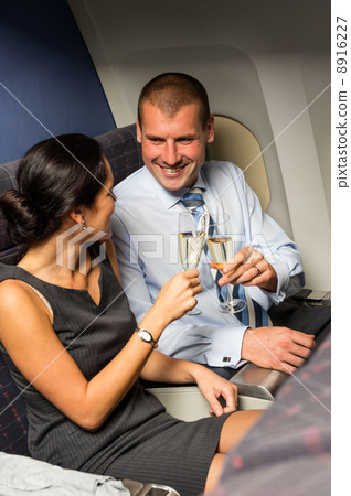 Smart couple travel by airplane toasting champagne Smart couple travel by airplane toasting champagne 8916227