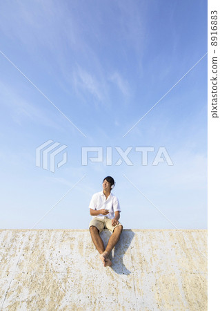 A man sitting on a breakwater 8916883