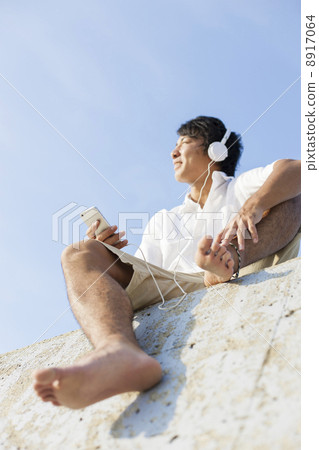 A man sitting in a breakwater and listening to music A man sitting in a breakwater and listening to music 8917064