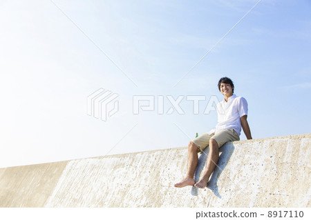 A man sitting on a breakwater 8917110
