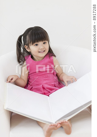 A girl who sits on a sofa and opens an album A girl who sits on a sofa and opens an album 8917288