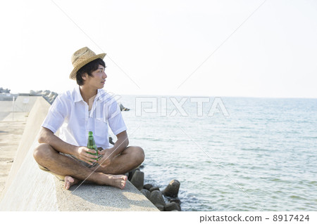 A man sitting on a breakwater 8917424