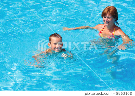 Mother train her son to swim in the pool. 8963168