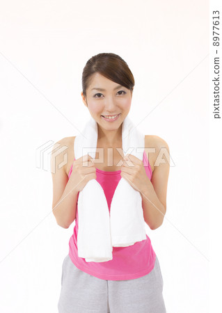 A young woman wiping sweat with a towel during training A young woman wiping sweat with a towel during training 8977613