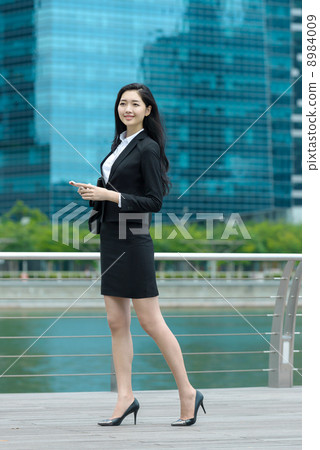 Pretty office lady using mobile along waterway 8984009