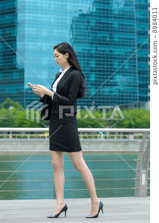 Pretty office lady using mobile along waterway 8984011