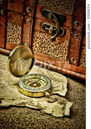 Old compass and old torn paper on a sandy beach Old compass and old torn paper on a sandy beach 8986654