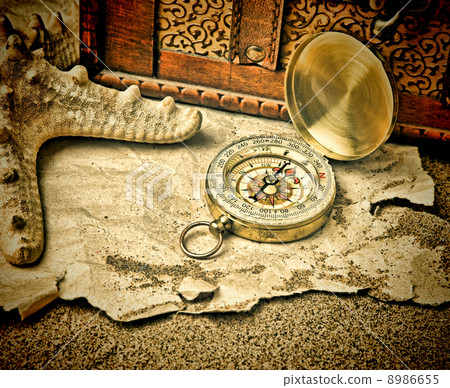 Old compass and old torn paper on a sandy beach Old compass and old torn paper on a sandy beach 8986655
