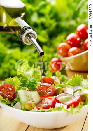 olive oil pouring over salad 8994830