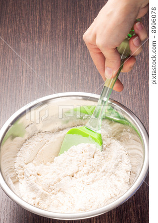 Mixing wheat flour in metallic bowl Mixing wheat flour in metallic bowl 8996078