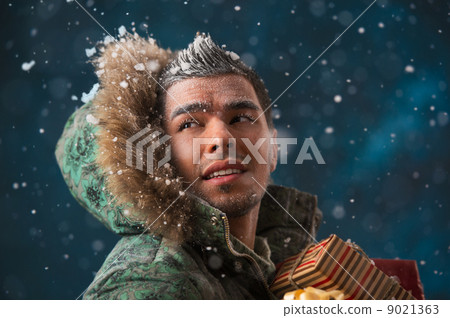Handsome man carrying christmas gifts outdoors in winter under s Handsome man carrying christmas gifts outdoors in winter under s 9021363