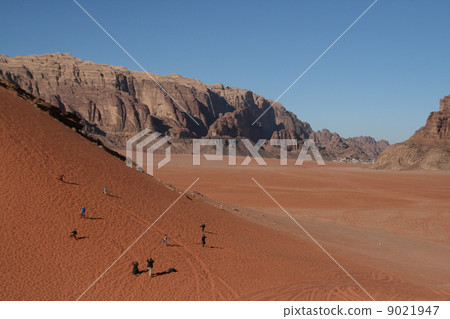 People running down with the dunes of Wadi Lam nature reserve in Jordan 9021947
