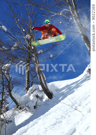 Snowboarder jumping against blue sky Snowboarder jumping against blue sky 9022169