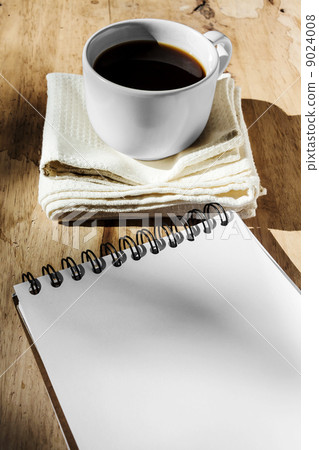 Sketchbook and instant coffee in white cup against wood backgrou 9024008