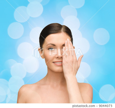 smiling young woman covering face with hand 9044073