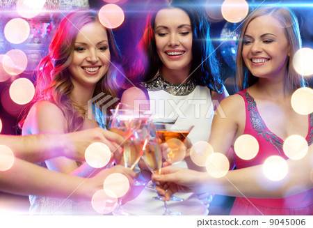 three smiling women with cocktails in club 9045006