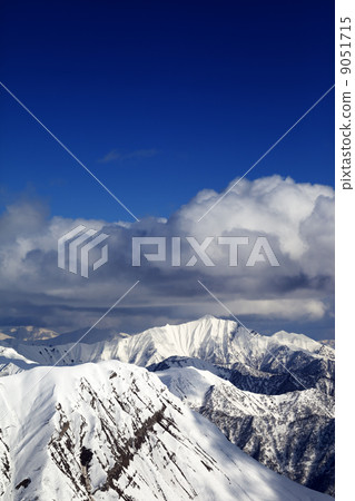 Winter snowy sunlit mountains and sky with clouds Winter snowy sunlit mountains and sky with clouds 9051715