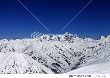 View on off-piste slope, winter snowy mountains and blue clear s 9051728