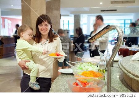 Woman with chid chooses   vegetables  in buffet 9055122