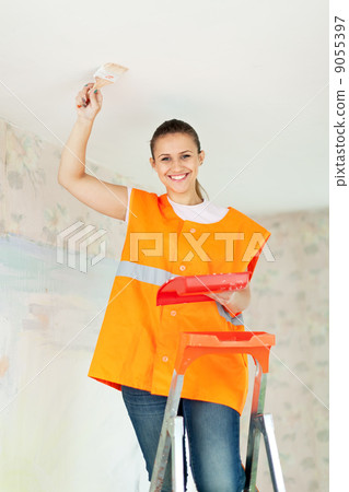 Female house painter paints the ceiling 9055397