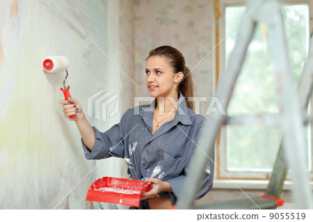 woman paints wall with roller woman paints wall with roller 9055519
