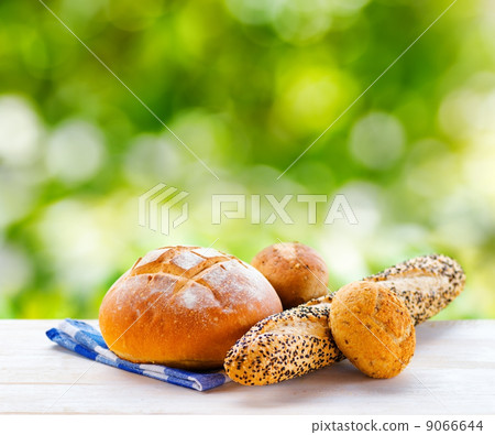 Fresh bread and checkered napkin on wooden table on rural backgr 9066644