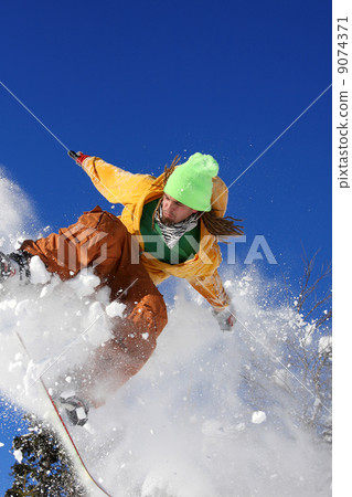 Snowboarder jumping against blue sky Snowboarder jumping against blue sky 9074371
