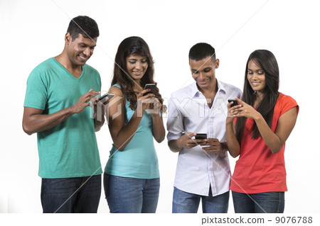Group of young Indian friends using their smartphones. Group of young Indian friends using their smartphones. 9076788