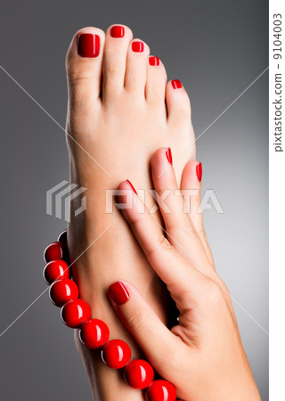 Closeup photo of a beautiful female feet with red pedicure Closeup photo of a beautiful female feet with red pedicure 9104003