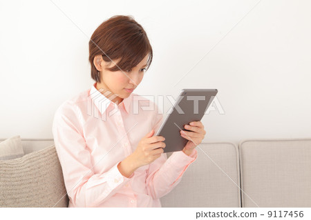 A woman watching a tablet on a sofa A woman watching a tablet on a sofa 9117456