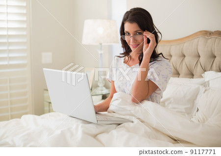 Cheerful pretty brown haired woman using a laptop Cheerful pretty brown haired woman using a laptop 9117771