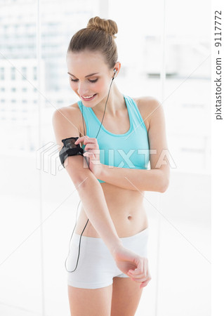 Sporty happy woman pressing a button on mp3 player 9117772