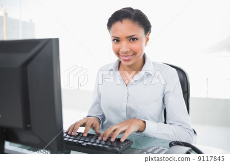 Content young dark haired businesswoman typing on her computer Content young dark haired businesswoman typing on her computer 9117845