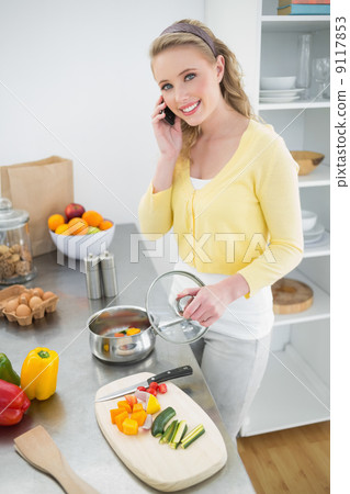 Cheerful cute blonde phoning and making dinner Cheerful cute blonde phoning and making dinner 9117853
