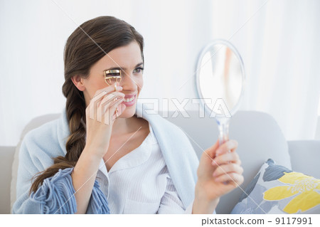 Concentrated casual brown haired woman in white pajamas using an 9117991