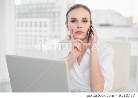 Thoughtful businesswoman using laptop and making a call looking 9118757