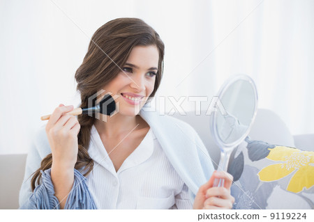 Cheerful casual brown haired woman in white pajamas applying pow 9119224