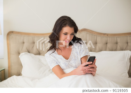 Concentrated pretty brown haired woman typing on a mobile phone 9119305
