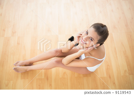 Smiling natural brown haired woman in white sportswear listening Smiling natural brown haired woman in white sportswear listening 9119543